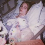 Sarah in her hospital bed with stuff animals.